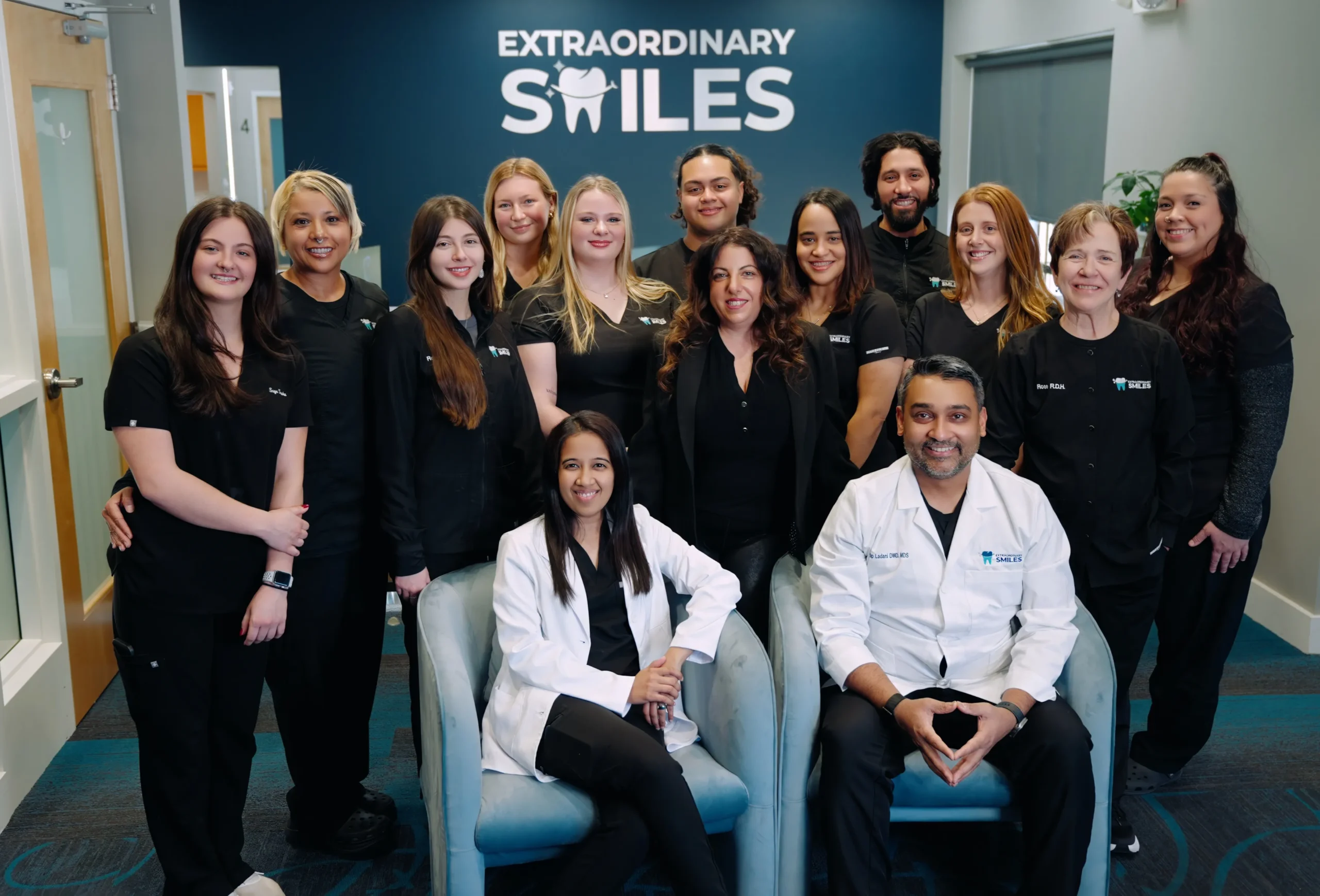 Full Extraordinary Smiles dental team group photo in front of the practice logo wall in Schnecksville, PA